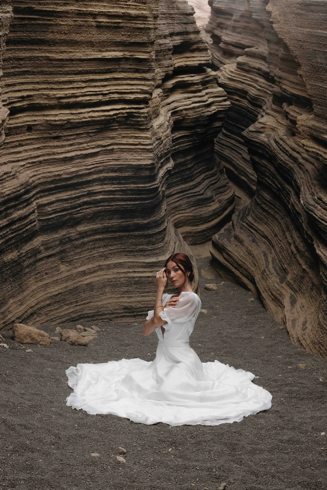 Mariée assise au fond d’un canyon, la jupe de la robe MELTEM02 étalée en corolle