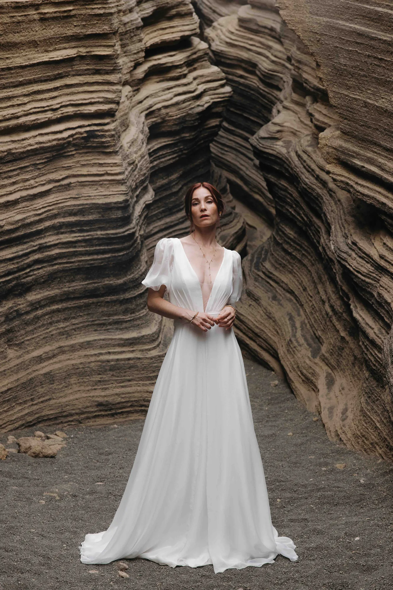 Robe MELTEM02 en mousseline de soie portée de face dans un canyon de roche, décolleté plongeant et manches ballon